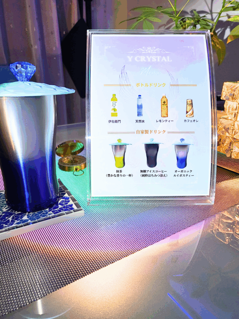 Yクリスタル探偵社の面談室にある来客用ドリンクメニュー。ペガサスのロゴ、クリスタル付きのコップ、手作りの飲み物メニューが載っている。