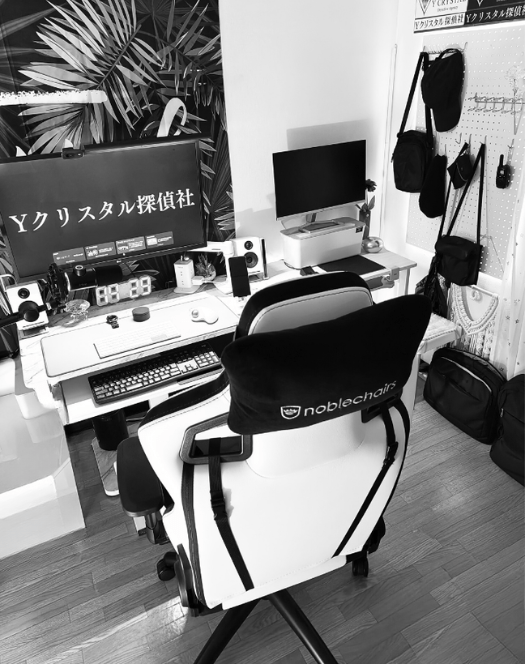 Yクリスタル探偵社の執務スペース。モニターに会社名が表示され、プロの探偵が集中して業務に取り組む様子をモノクロで表現。